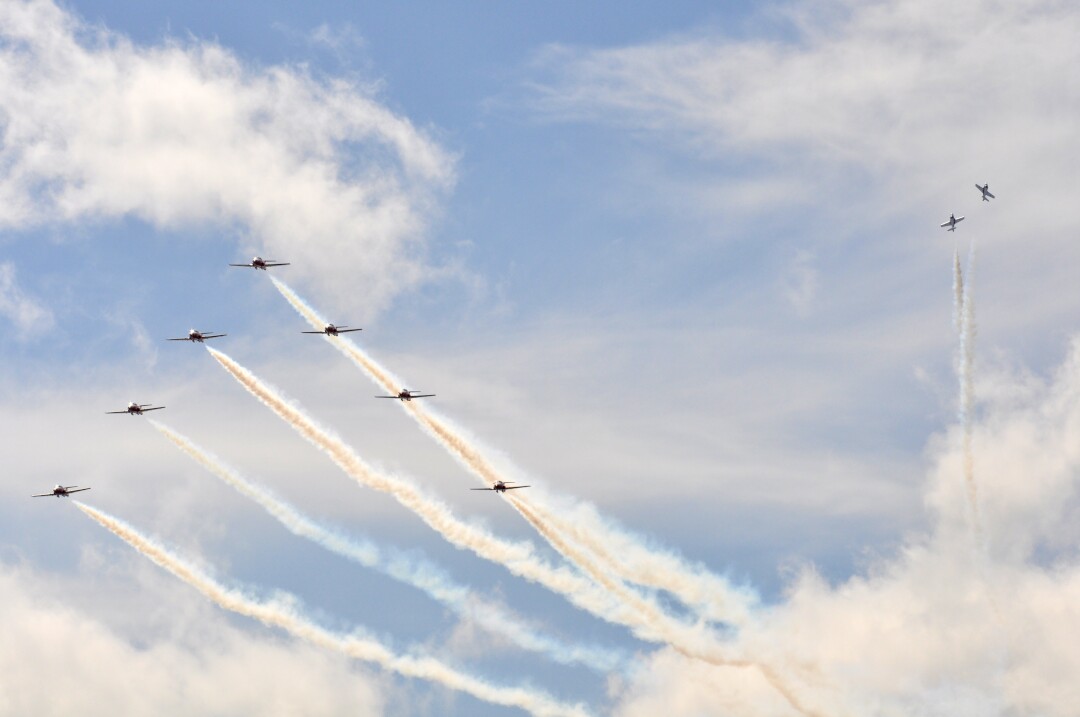 The Snowbirds flying team in formation against a blue and cloudy sky