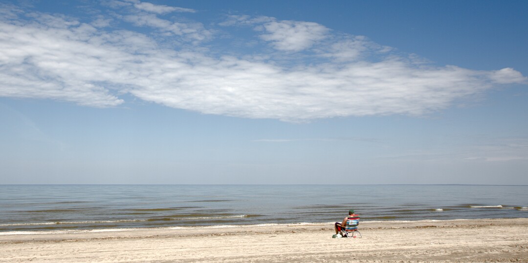 A man sitting alone in a lawn chair on the beach
